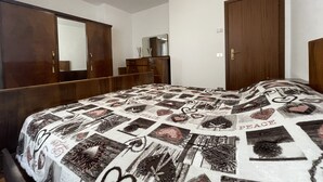 Un dormitorio con cama, armario, espejo y puerta.