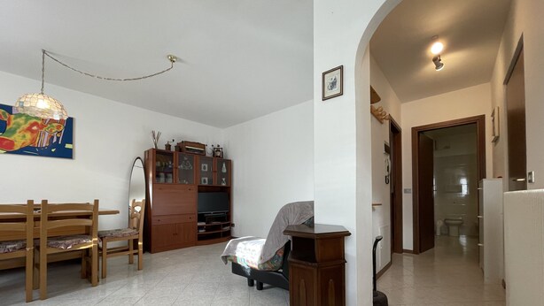 Un salón amplio con un banco de madera, un televisor y un aparador.