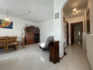 A spacious living room with a wooden bench, a television, and a cabinet.