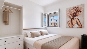 Ein Schlafzimmer mit einem Bett, einem Kleiderschrank, einem Fenster und einem Gemälde.