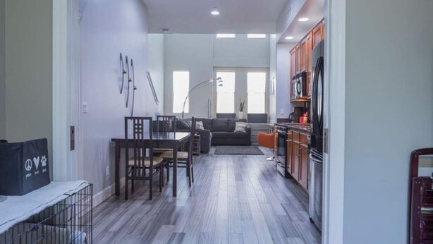 Una cocina moderna con armarios de madera, un refrigerador y un comedor con mesa y sillas.
