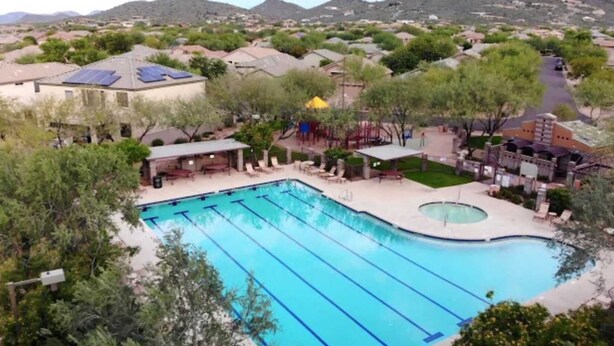 A swimming pool with multiple lanes, surrounded by trees and a small deck area with lounge chairs. - North Phoenix Condo – Sunset Views + Community Heated Pool (Phoenix)