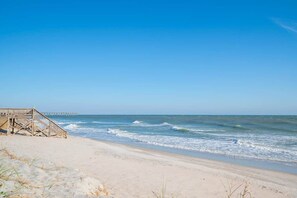 A beach with a wooden boardwalk leading to a pier. - Ruffians Roost (Carolina Beach)