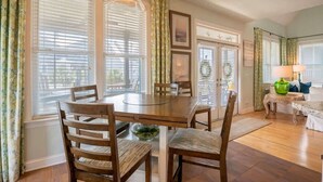 Een eetruimte met een ronde houten tafel, vier houten stoelen en een hanglamp.