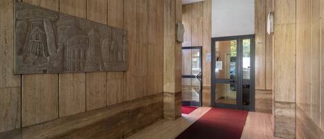 A hallway with wooden paneling and a red carpet.