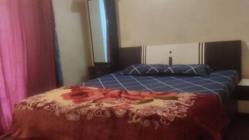 A bedroom with a bed, a nightstand, a mirror, and a curtain.