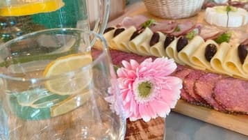 A table with a glass pitcher, a pink flower, and various food items.