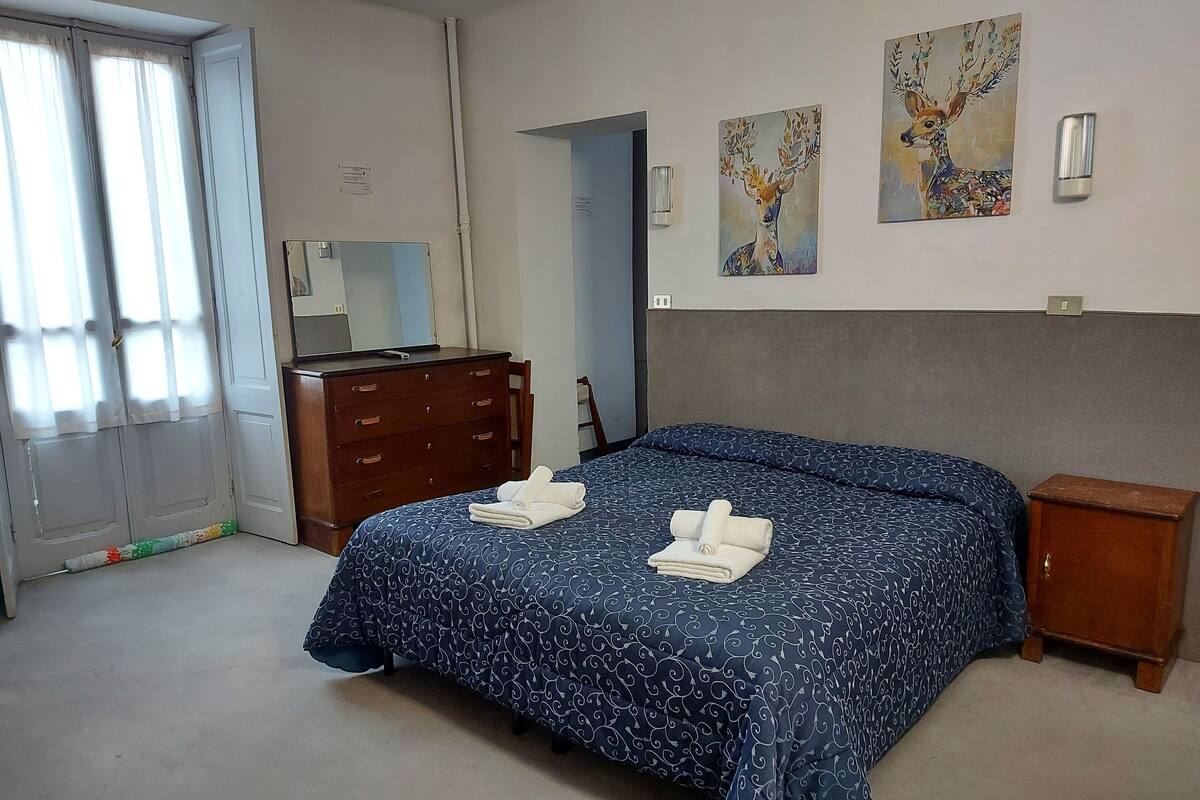 Une chambre à coucher comprenant un lit, une commode, une table de chevet et deux tableaux accrochés au mur.