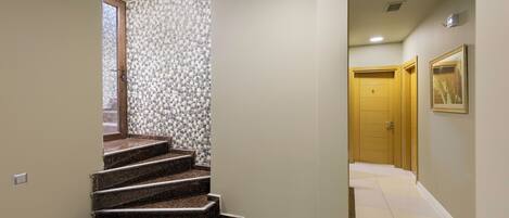 A staircase leading to a landing with a patterned wall and a door in the background.