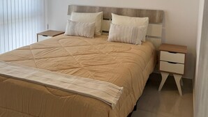 Un dormitorio con una cama grande, dos mesitas de noche y una mesita auxiliar.