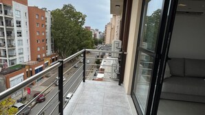 Un balcón con vistas a una calle de la ciudad, una puerta de cristal y un sofá.