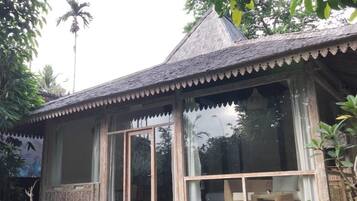 Una casa de madera tradicional con techo de paja, ventanas grandes y una escalera de piedra que lleva a la entrada.