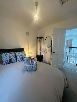 A bedroom with a bed, bedside table, lamp, and a door leading to a balcony.