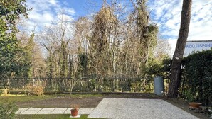 Ein gepflasterter Außenbereich mit einem kleinen Blumenbeet und einer Blumentopfpflanze.
