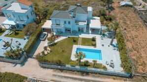 A large, modern house with a swimming pool, multiple balconies, and a well-maintained garden. - Villa Yiayia: Relaxing by the sea (Heated pool) (Sisi)