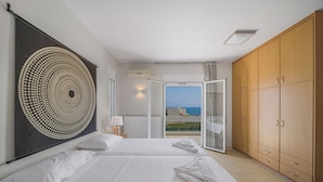 A hotel room with two beds, a large artwork on the wall, and a view of the sea through an open door. - Villa Yiayia: Relaxing by the sea (Heated pool) (Sisi)