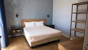 Quarto com cama, duas mesas de cabeceira, um criado-mudo, uma estante de madeira e uma cortina azul.