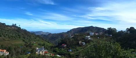 A rural landscape with terraced fields, scattered houses, and a clear blue sky.