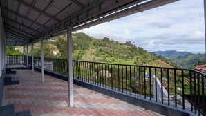 Varanda coberta com vista para um vale verde e colinas.