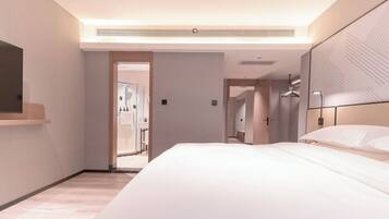 Una habitación de hotel moderna con una cama grande, una mesita de noche, un espejo y un vestidor.