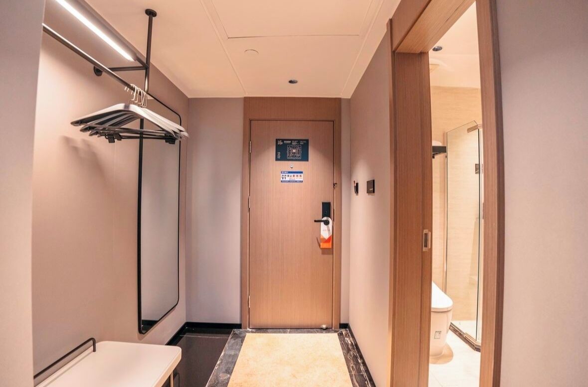 Passadís d'hotel amb una porta de fusta, un penjador i una taula petita.