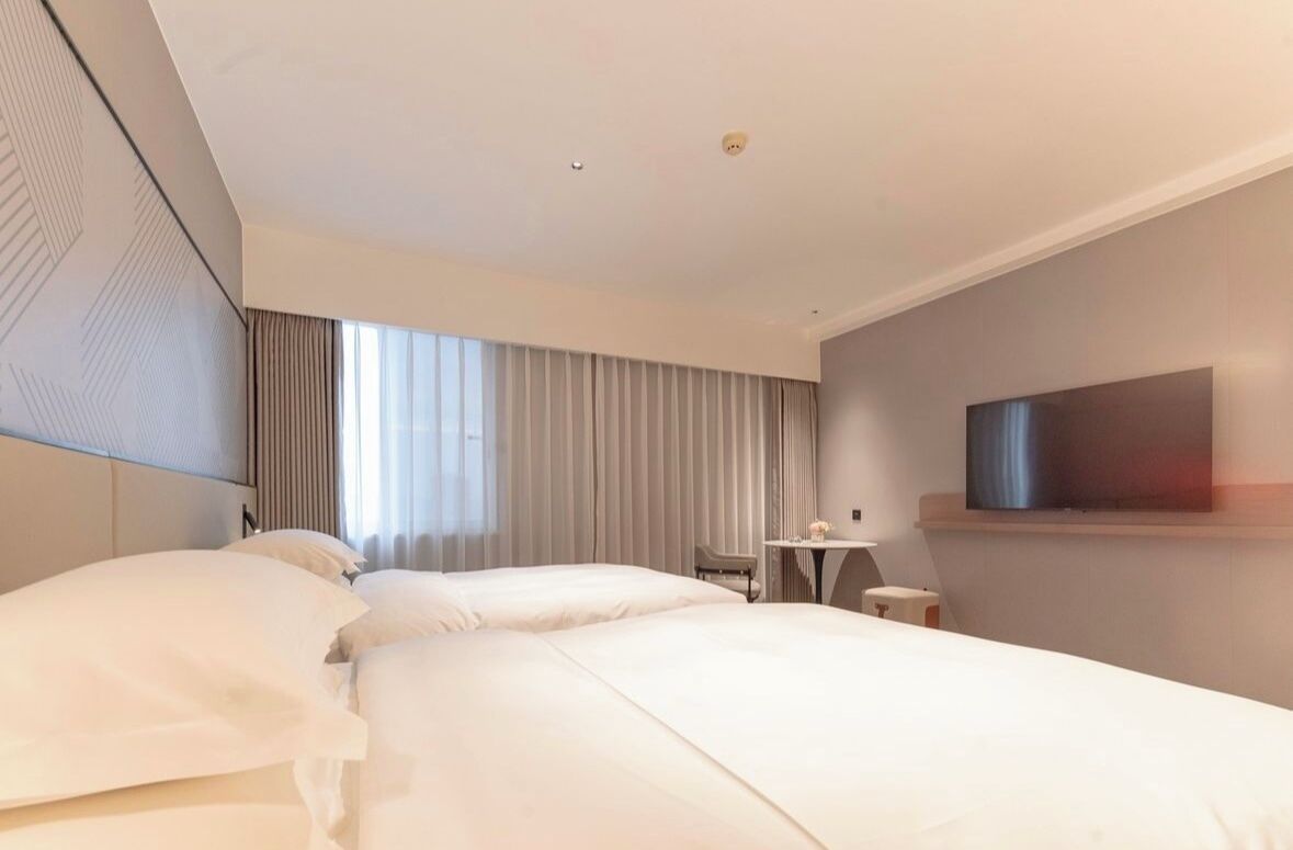 Una habitación de hotel moderna con una cama grande, un escritorio y un televisor de pantalla plana montado en la pared.