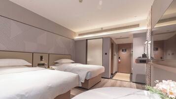 A modern hotel room with two beds, a large mirror, and a small bathroom.
