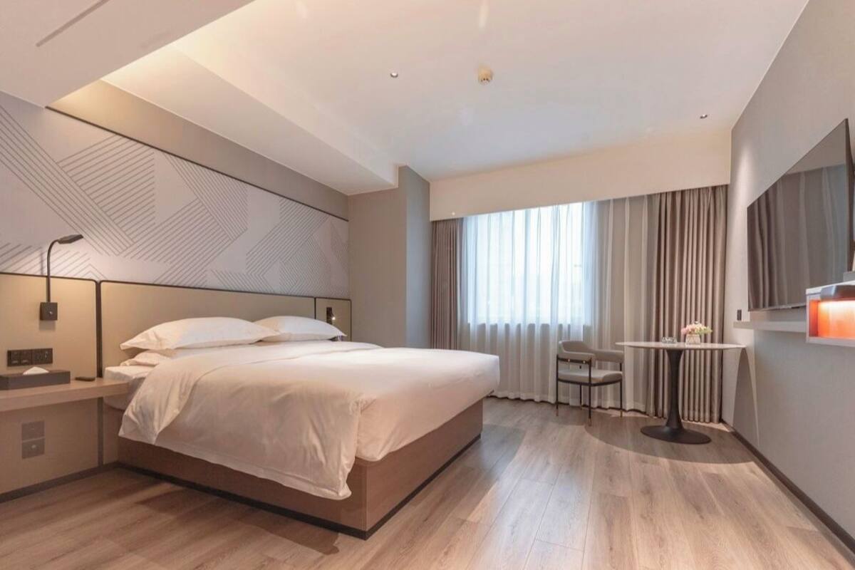 Ett modernt hotellrum med en stor säng, sängbord, ett skrivbord och en stol.