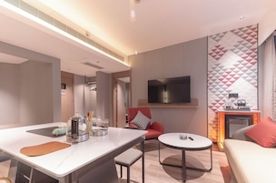 Quarto de hotel moderno com área de refeições, sofá, televisão e lareira.