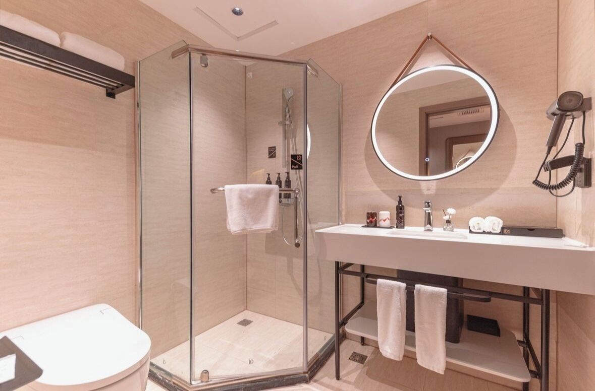 Une salle de bain moderne avec une douche à parois de verre, un lavabo blanc avec un miroir et des toilettes.
