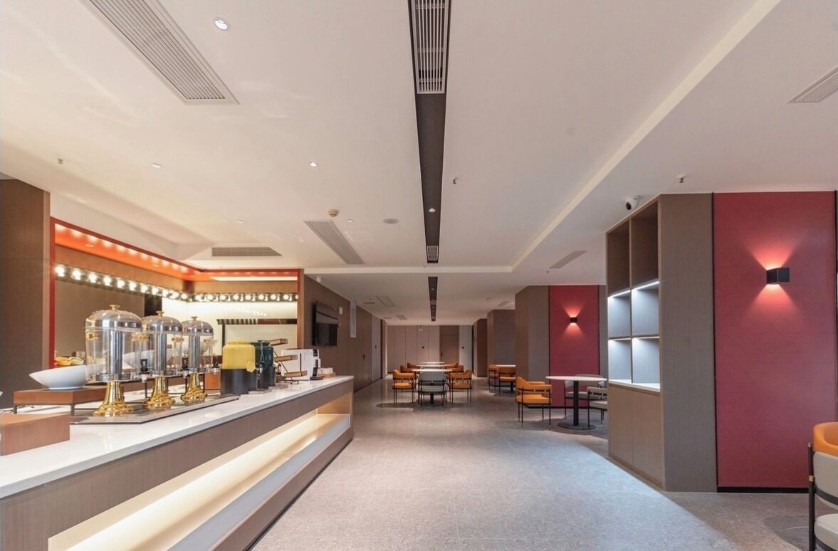 A modern hotel lobby with a reception desk, seating area, and built-in shelving.