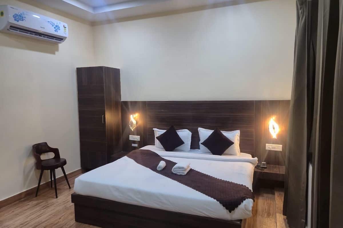 Quarto de hotel com uma cama grande, cabeceira em madeira escura, duas mesinhas de cabeceira e uma cadeira.