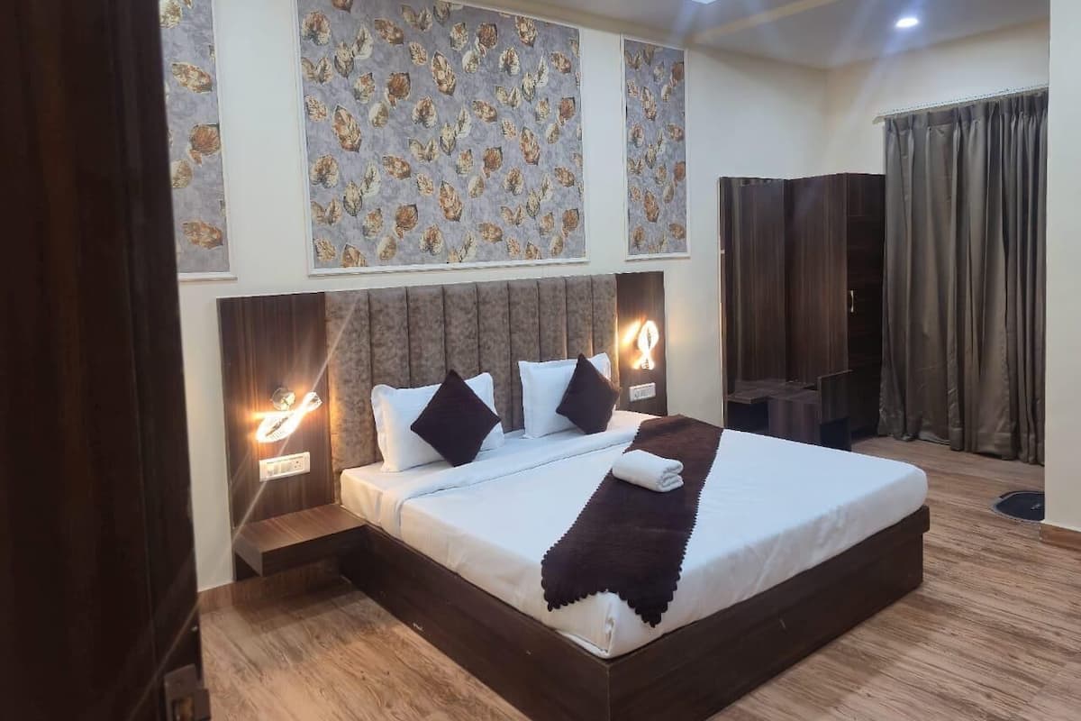 Quarto de hotel moderno com uma cama grande, duas mesas de cabeceira com abajures, uma cabeceira e uma janela ampla com cortinas.
