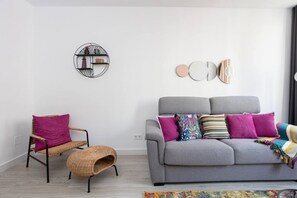 A modern living room with a grey sofa, a wicker chair, and a small side table.
