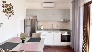 A compact kitchen with a refrigerator, stove, sink, and a dining area with chairs and a table.