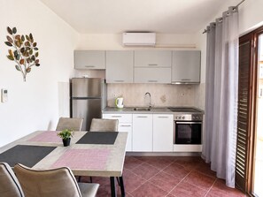 A compact kitchen with a refrigerator, stove, sink, and a dining area with chairs and a table.