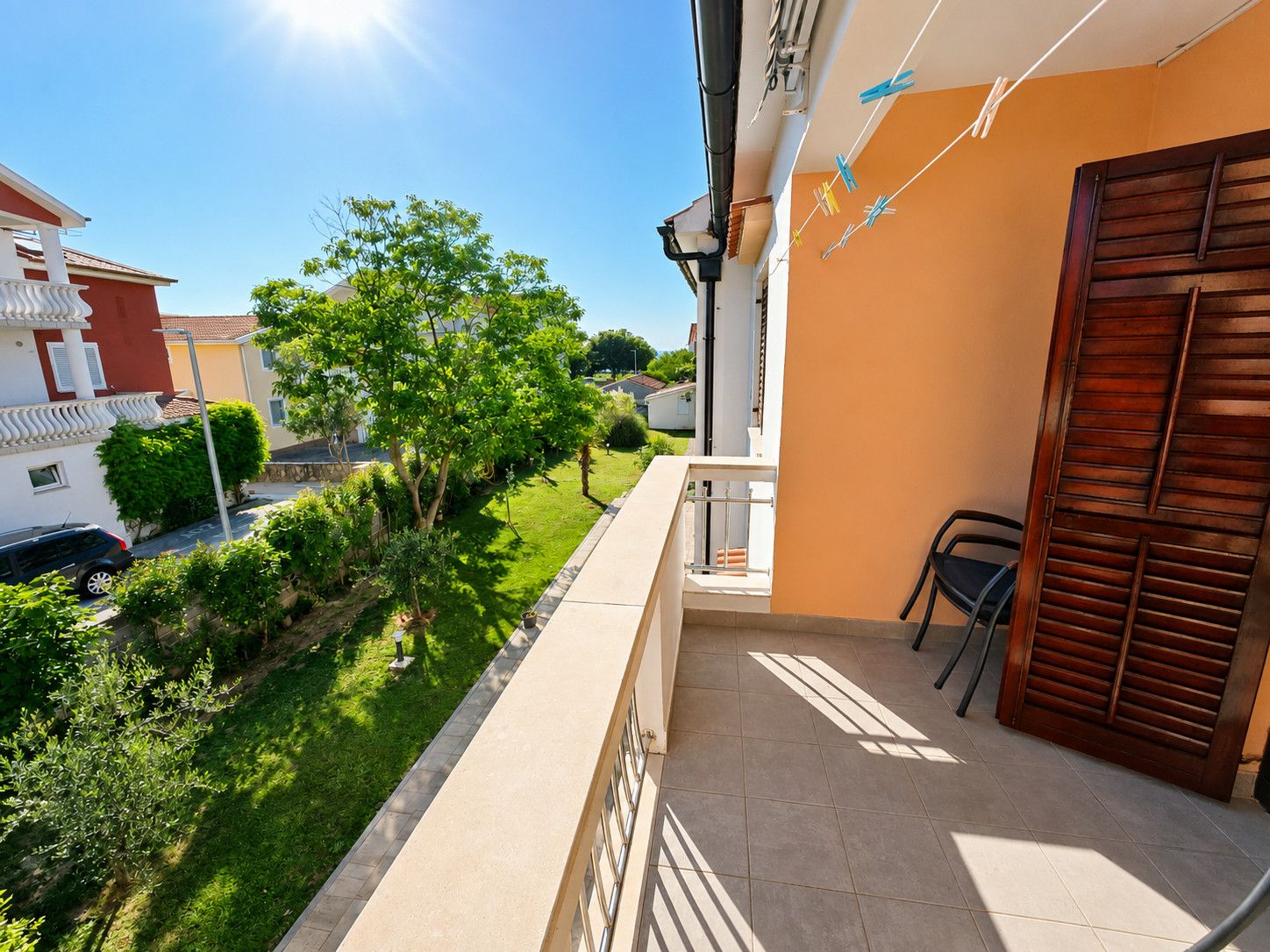 Un balcon d’habitation donnant sur une pelouse verdoyante et les maisons voisines.