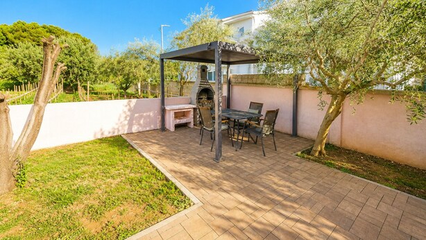 An outdoor patio with a grill, seating, and a pergola structure.