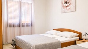 A bedroom with a bed, bedside table, lamp, and a wall-mounted flower painting.