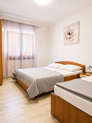 A bedroom with a bed, bedside table, lamp, and a wall-mounted flower painting.