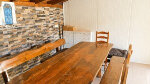 A wooden dining table with benches, a stone wall, and a wooden ceiling.