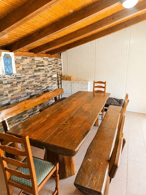 A wooden dining table with benches, a stone wall, and a wooden ceiling.