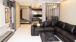 Een moderne woonkamer met een modulaire bank, een salontafel en een trap naar een verdieping erboven.