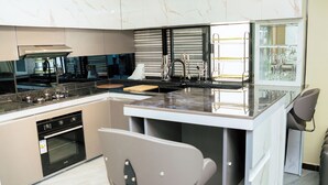 Een moderne keuken met een marmeren achterwand, roestvrijstalen apparatuur en een groot kookeiland met barkrukken.