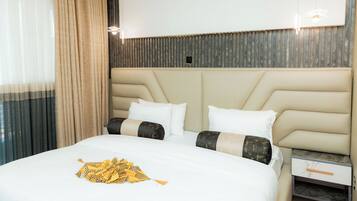 Een hotelkamer met een groot bed, een hoofdbord met verticale latten, een nachtkastje en een aan de muur bevestigde televisie.