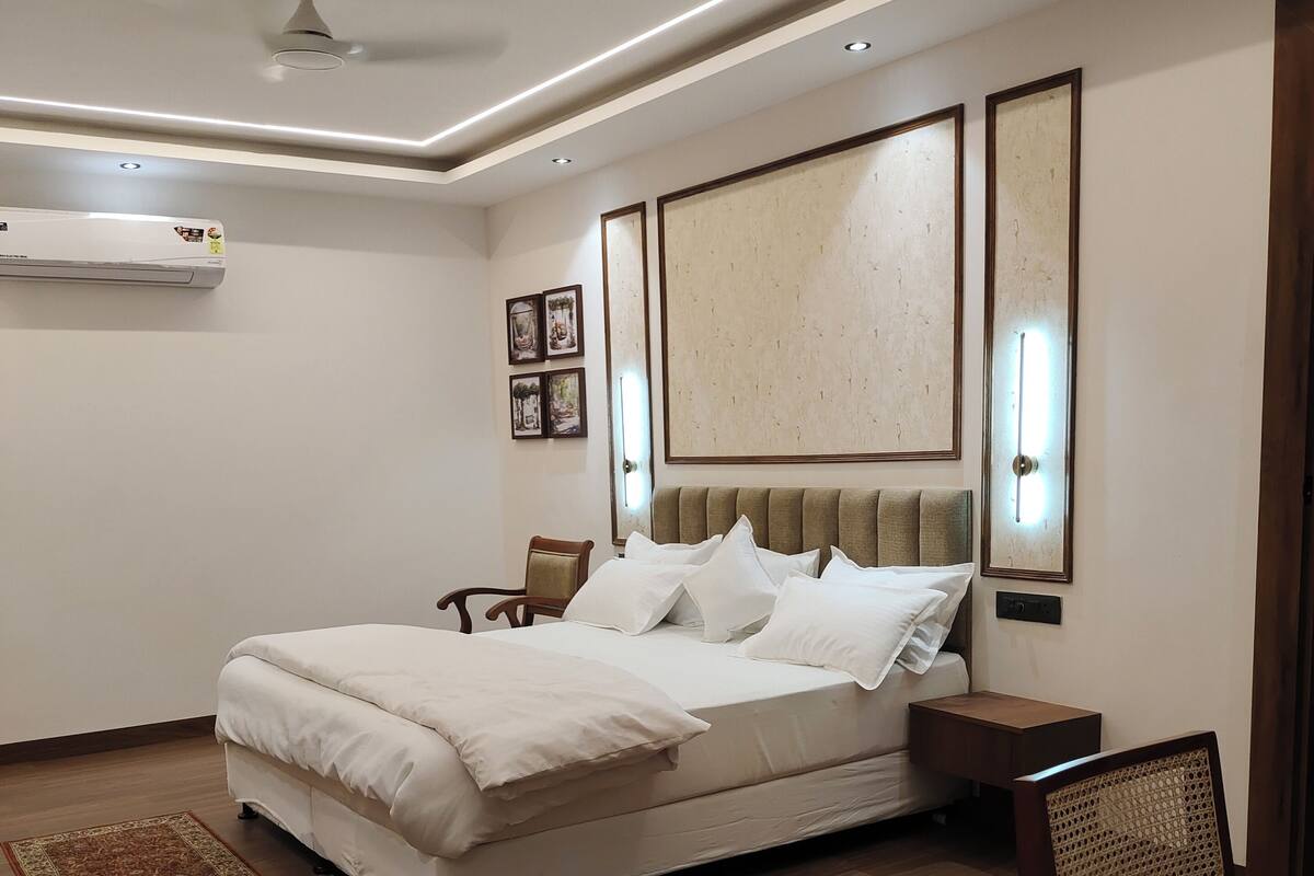 A modern bedroom with a large bed, bedside tables, a chair, and a ceiling fan.