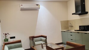 Un salon comprenant un canapé, une table basse et un ventilateur de plafond. Il y a également un coin cuisine avec un four à micro-ondes et une cuisinière.