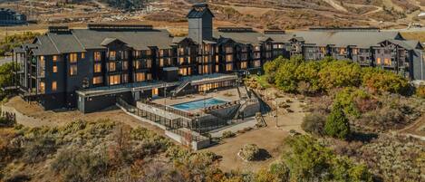 Un gran complejo turístico con varias edificaciones, una piscina y montañas al fondo.