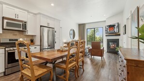 A modern kitchen with white cabinetry, stainless steel appliances, and a wooden dining table with chairs.