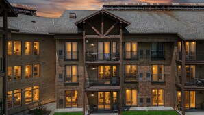A multi-story building with balconies, large windows, and a well-maintained lawn.